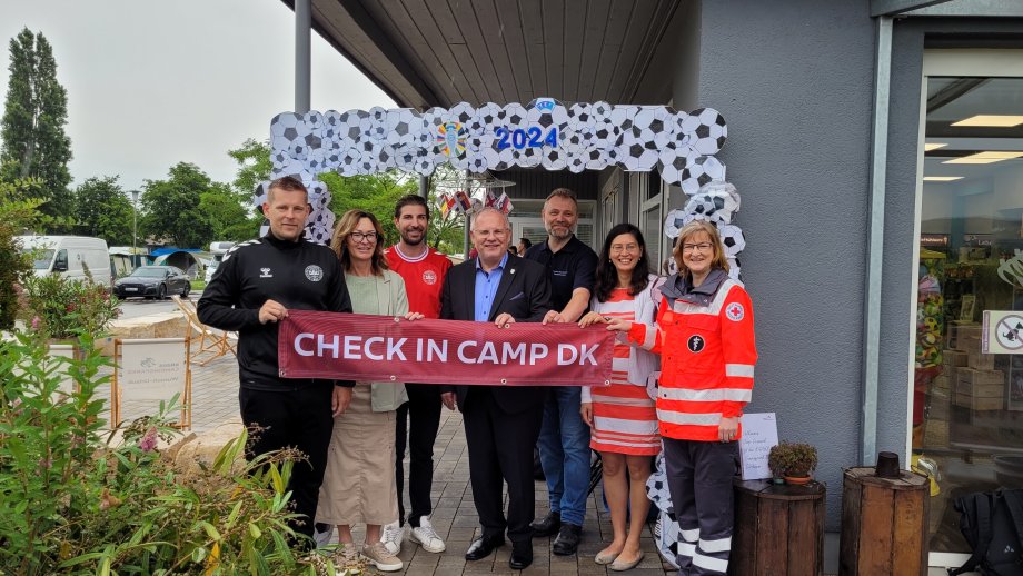 Eine Gruppe Menschen vor einem Deko-Fußball-Bogen mit einem Banner "Check In Camp DK".