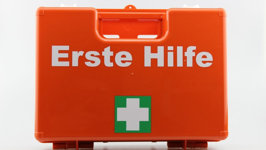 Orangefarbener, kleiner Koffer mit der Aufschrift "Erste Hilfe".