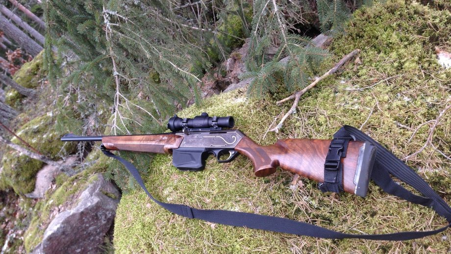 Ein Jagdgewehr liegt auf einem moosigen Fels im Wald.