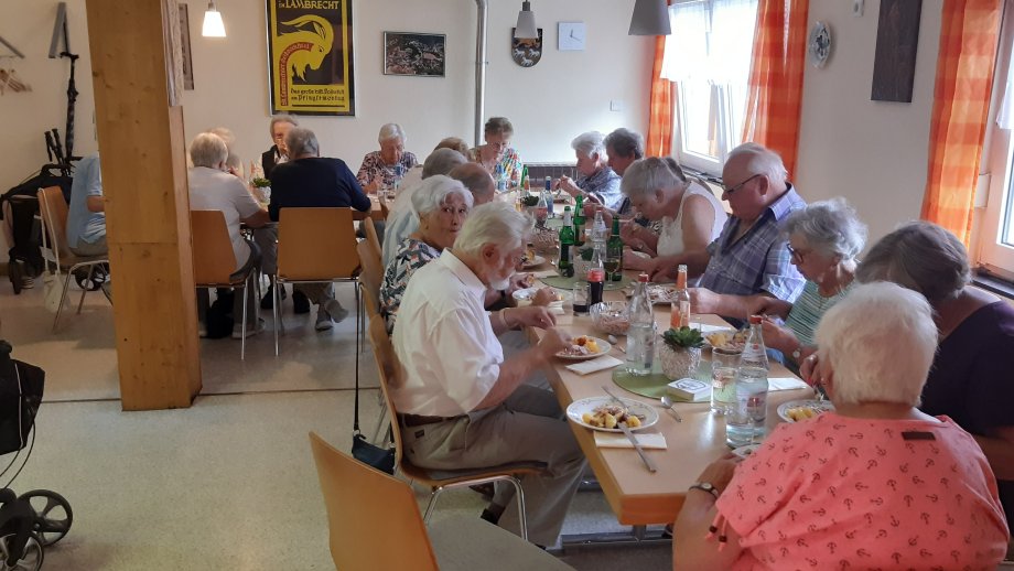 Seniorinnen und Senioren sitzen zusammen beim Essen. 