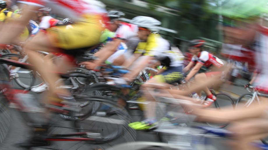 Eine Gruppe Radsportler fährt bei einem Rennen schnell vorbei, Bild leicht verschwommen.