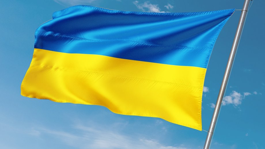 Eine ukrainische Fahne weht vor blauem Himmel. 